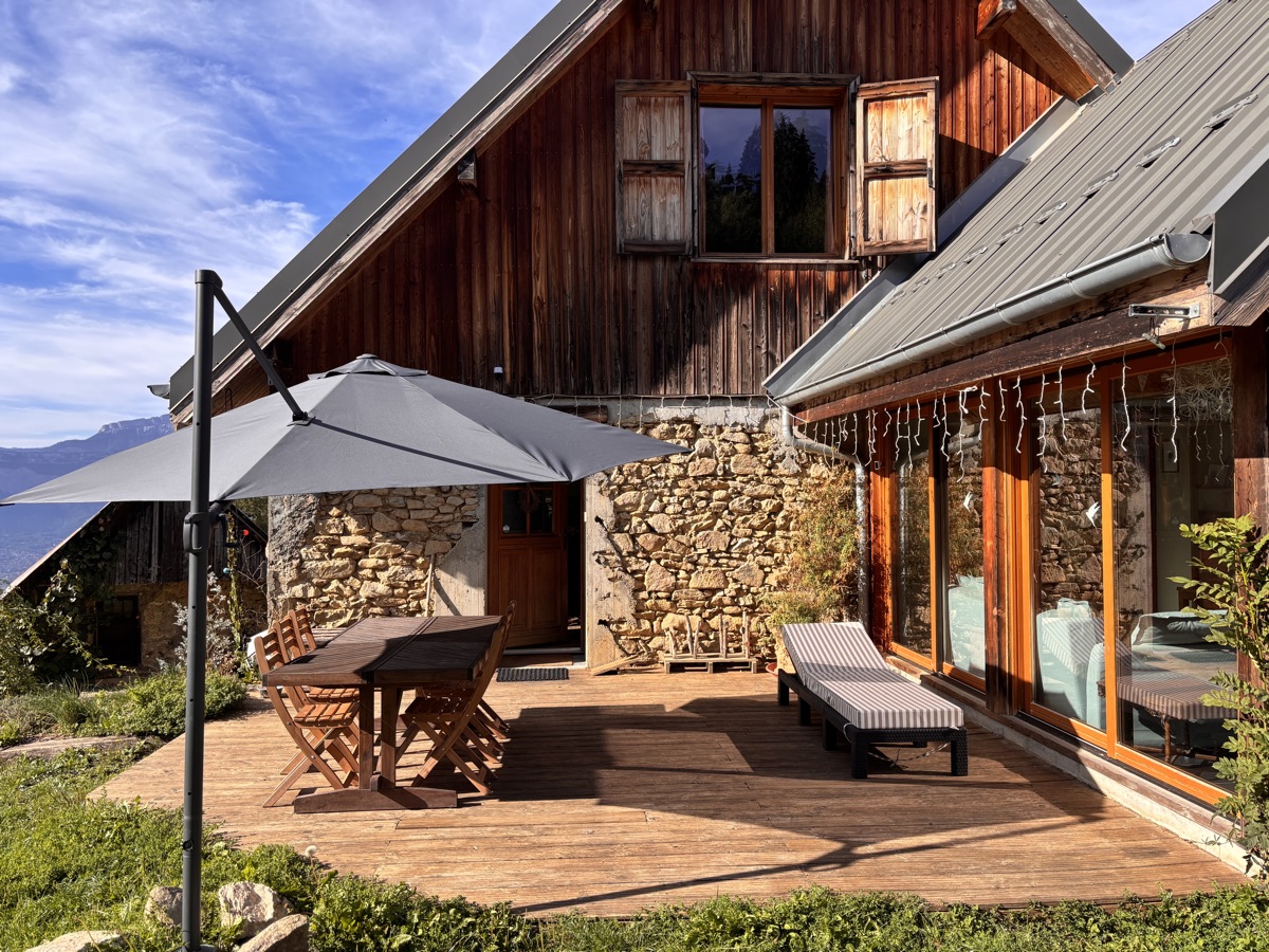 Le gîte et sa terrasse en bois, avec transats et vue sur la montagne