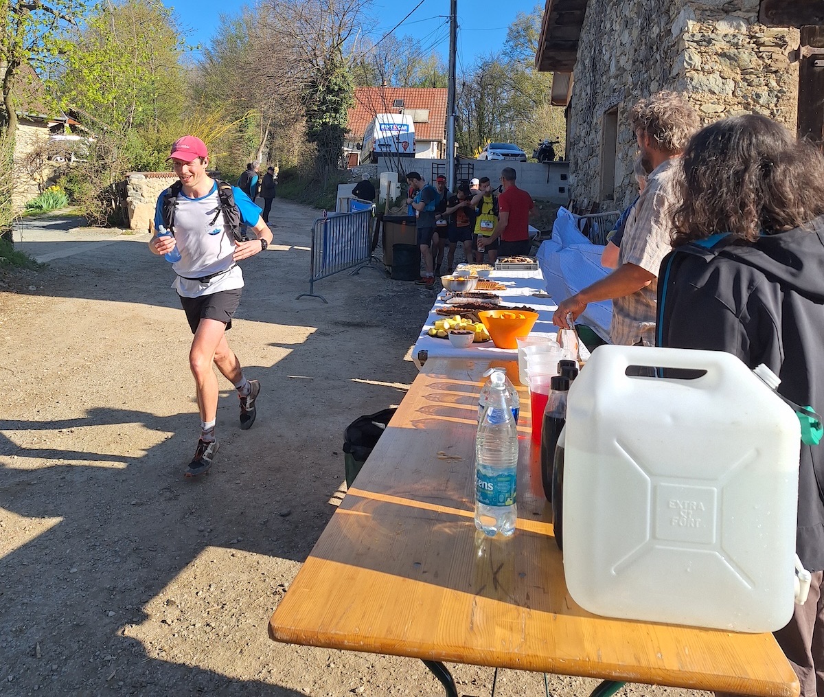 Coureur à un ravitaillement de course, table garnie de produits de la ferme